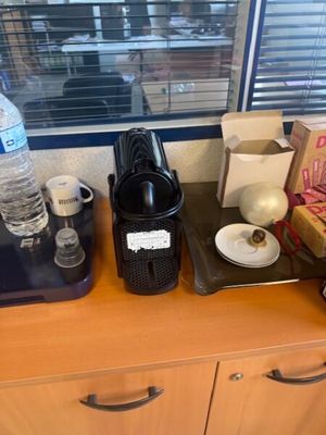 a coffee maker on the counter next to a cup of coffee