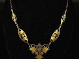 a gold necklace on a black mannequin with a black background
