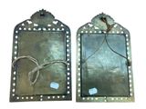 pair of antique metal mirrors with holes and rope hang on the wall