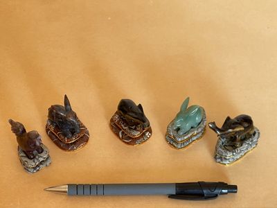 cinq figurines d'animaux et un stylo posés sur une table