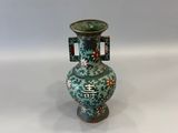 un vase vert avec des fleurs posé sur une table