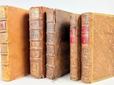 plusieurs vieux livres sont alignés sur une surface blanche