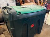 a large green container sitting on the floor next to a pile of wood