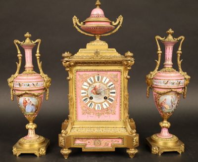 trois vases roses et dorés et une horloge posés sur une table