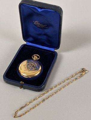 a gold pocket watch in a blue case with a gold chain