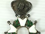 an image of a metal cross with green and white decorations on it