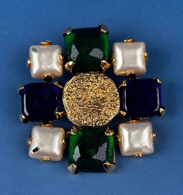 an image of a brooch with pearls and a gold coin on a blue background