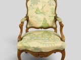 une vieille chaise dont le dossier est recouvert de tissu vert et blanc