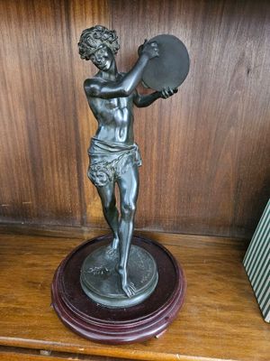 une statue représentant un garçon tenant un éventail, posée sur une étagère