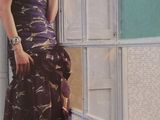 a woman in a purple dress standing by a wall