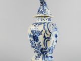 a blue and white vase with a bird on top of it