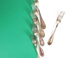 five forks and a knife on a green and white table