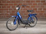 an image of a blue electric bike parked in front of a brick wall