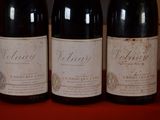 three bottles of wine are lined up on a red table