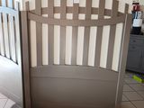 a baby crib with a wooden gate in the middle of the room