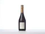 a bottle of wine sitting on top of a table next to a white wall