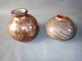 two small vases sitting on a table next to each other