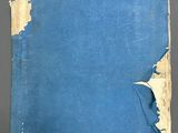 an old blue book with torn pages sitting on top of a table