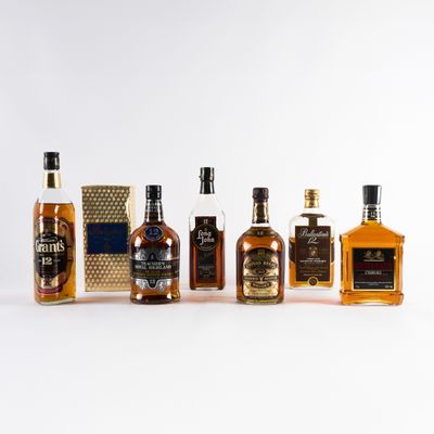 Plusieurs bouteilles de différents types de whisky sont alignées sur une surface blanche