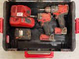deux outils électriques rouges dans une boîte à outils posée par terre