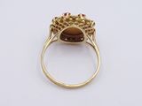 a gold ring with a brown stone surrounded by pink stones