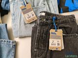 several pairs of jeans are on a table with a price tag