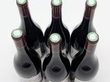 six bottles of wine are lined up in a row on a white surface
