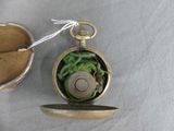 a gold pocket watch with a green dragon inside of it