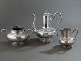 trois théières en argent et deux tasses en argent posées sur une table