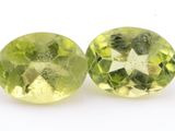 a pair of two green and white gems on a white surface