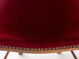 the back of a red velvet chair with studded legs