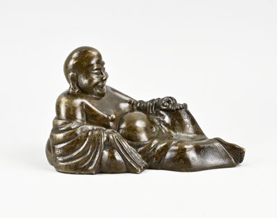 une statue en bronze représentant un bébé assis sur un oreiller