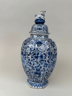 un vase bleu et blanc surmonté d'un oiseau