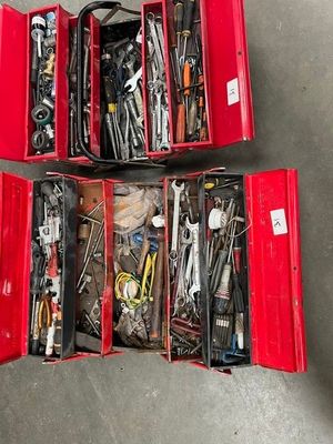 deux boîtes rouges posées par terre, contenant des outils