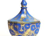 a blue and gold bowl with a lid on a white surface