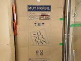 une boîte en carton sur laquelle est accrochée une pancarte, dans une pièce