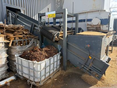 un gros tas de bois dans un conteneur à côté d'un bâtiment