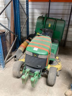 une tondeuse à gazon verte garée dans un garage à côté d'un tracteur vert