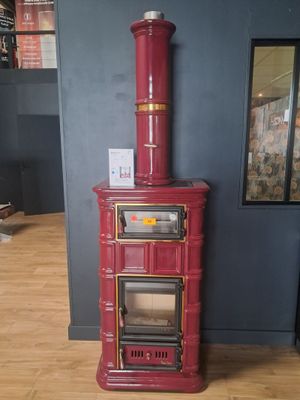 un poêle rouge posé sur un plancher en bois dans une pièce