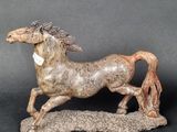 figurine of a horse running on a rock with a black background