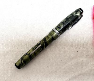 a pen that is laying on a table next to a pink pen