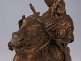 bronze statue of a man riding a horse with a hat on his head