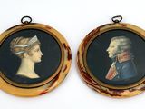 deux portraits encadrés représentant un homme et une femme sur fond blanc