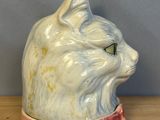 a white cat head with a pink collar on a wooden table