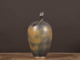 a vase with a bird on top of it on a table