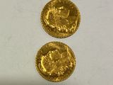 two gold coins sitting on top of each other on a white surface