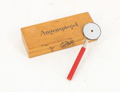 une boîte en bois munie d'une poignée rouge et d'une loupe posée dessus