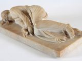 statue of a man laying on a bed with a dog on it