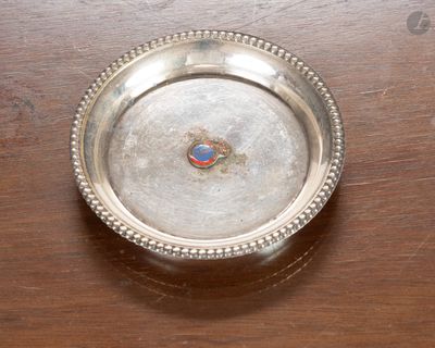 une assiette en argent posée sur une table en bois, avec un bouton rouge et bleu