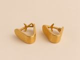 une paire de boucles d'oreilles en or sur un fond beige